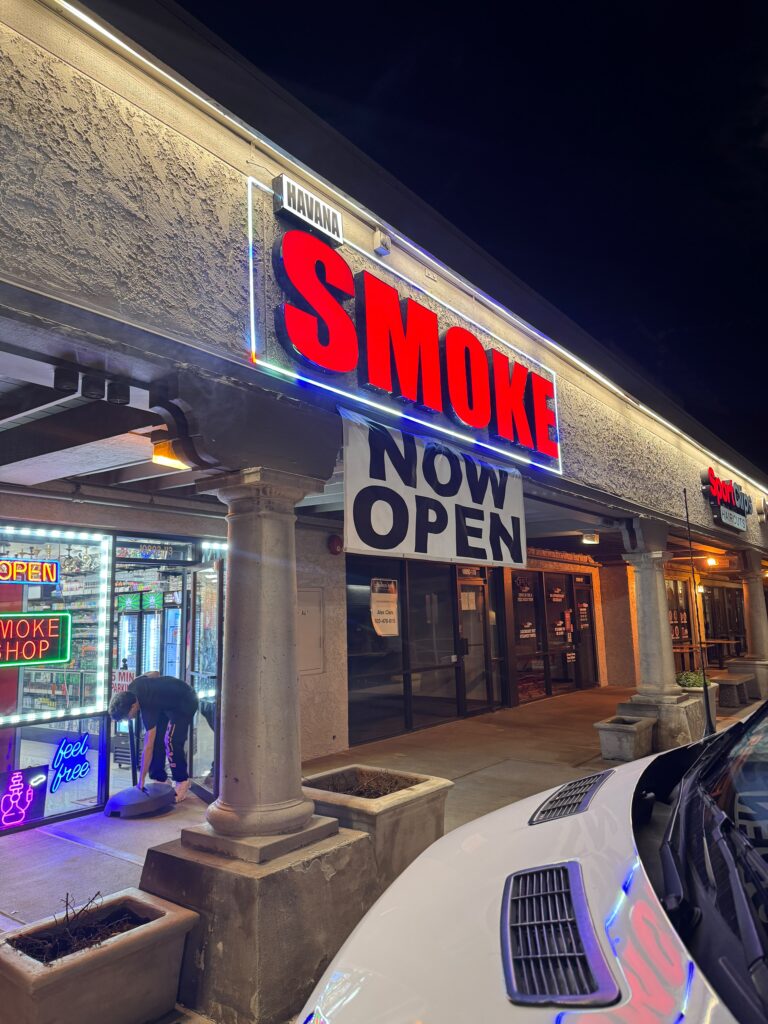 Red illuminated channel letter sign on a storefront at night